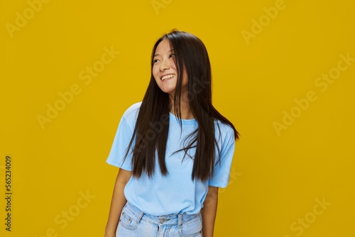 Asian woman smile with teeth hand gestures, signs and symbols on yellow background in blue t-shirt and jeans
