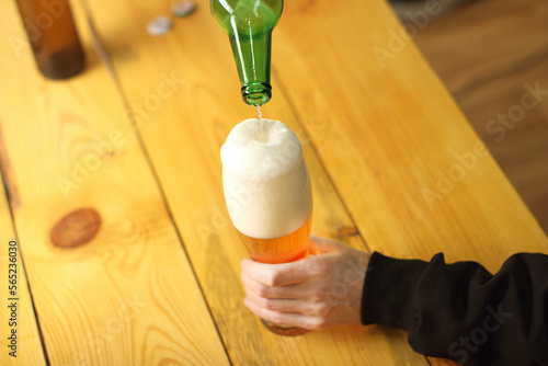 pouring beer from a green bottle into a mug