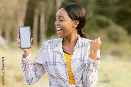 Black woman, phone and mockup display for winning, discount or sale with smile in nature. Happy African American female smiling for giveaway prize, deal or achievement on smartphone in the outdoors © Jade Maas/peopleimages.com