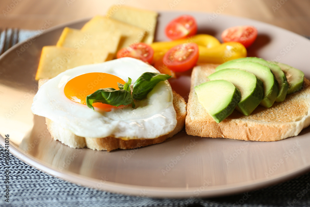 Tasty toasts with fried egg, avocado, cheese and vegetables on table, closeup Tasty toasts with fried egg, avocado, cheese and vegetables on table, closeup