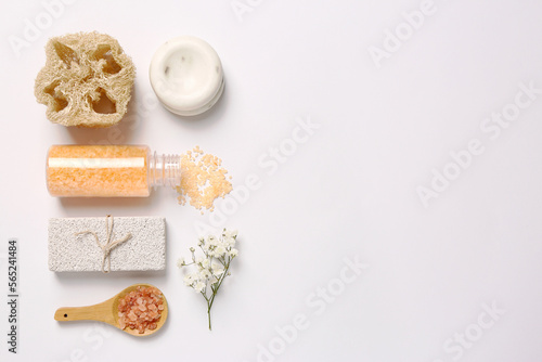 Sea salt, soap bar, beautiful flowers and loofah on white background, flat lay. Space for text
