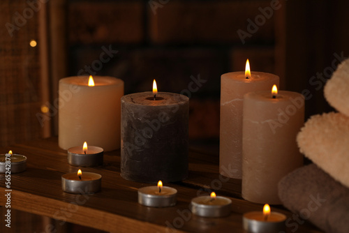 Spa composition with burning candles and towels on wooden table in wellness center