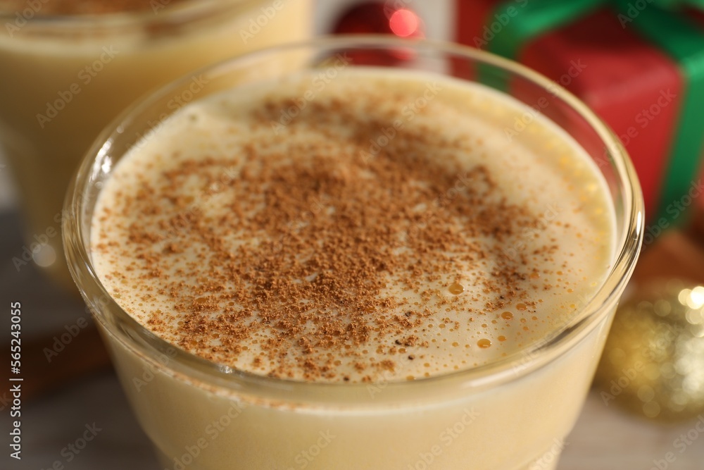 Tasty eggnog with cinnamon in glass on table, closeup Tasty eggnog with cinnamon in glass on table, closeup