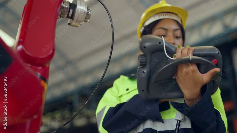 Female engineer controlling robot arm in modern factory. She checking the operation of robot arm. Technology, automation, innovation and engineering concept. Female engineer controlling robot arm in modern factory. She checking the operation of robot arm. Technology, automation, innovation and engineering concept.