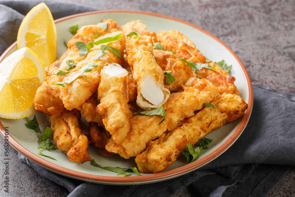 Deep Fried Breaded calamari strips with lemon closeup on the plate on the table. Horizontal Deep Fried Breaded calamari strips with lemon closeup on the plate on the table. Horizontal