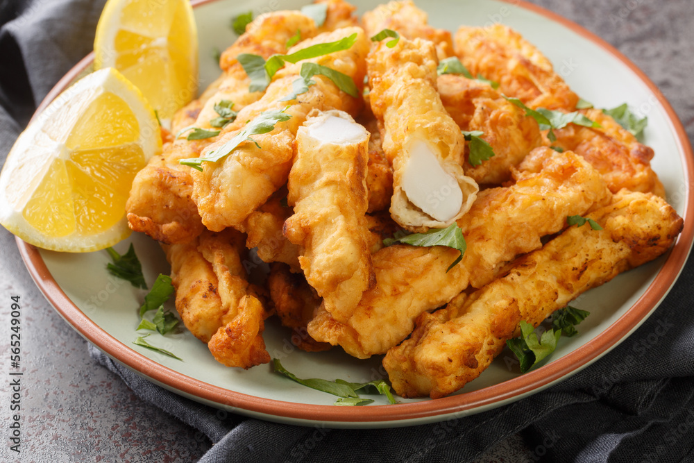 Hot breaded calamari strips served with lemon wedges closeup on the plate on the table. Horizontal Hot breaded calamari strips served with lemon wedges closeup on the plate on the table. Horizontal