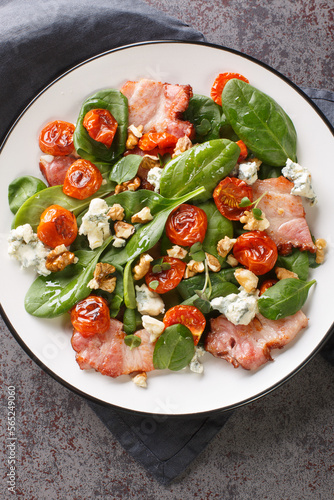 French Aveyronnaise salad is made with bacon and Roquefort cheese as its main ingredients closeup on the plate on the table. Vertical top view from above