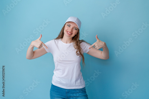 Shopping concept. Surprised cute caucasian girl checking discounts, pointing fingers down and looking surprised, wearing a white t-shirt for mockup speaking on a blue background.