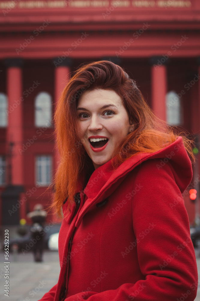 Close up excited woman wearing red coat on street portrait picture. Closeup side view photography with city building on background. High quality photo for ads, travel blog, magazine, article