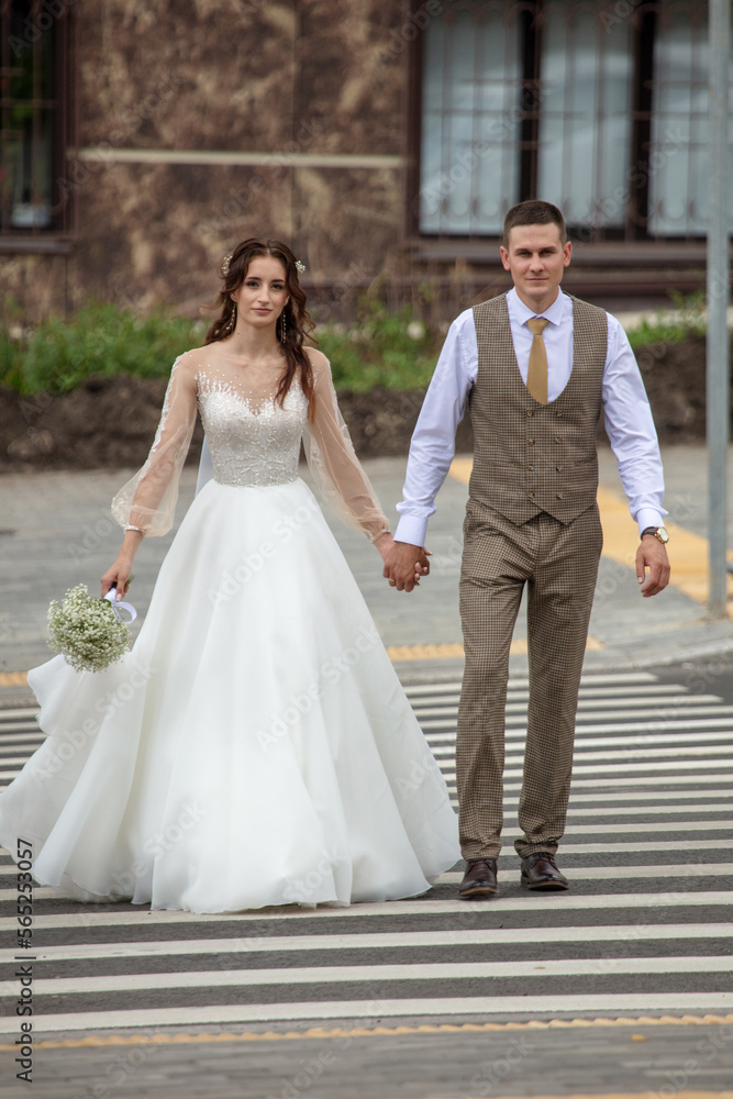 The bride and groom in a wedding dress on a pedestrian crossing.