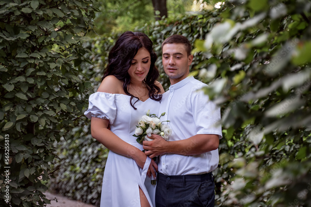 Cute newlyweds hugging and smiling in a green park. Portrait of bride and groom in lace dress Cute newlyweds hugging and smiling in a green park. Portrait of bride and groom in lace dress
