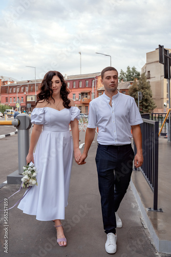 Romantic walk through the old town. Newlyweds walk around the city. Urban wedding. The beautiful bride and groom walk along the asphalt road in the old town. © Оксана Олейник