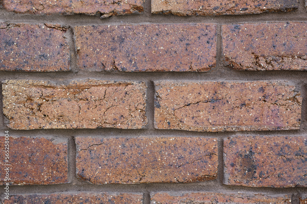 Fototapeta premium Extreme close-up brownish crimson coloured coarse rustic house bricks with vertical and horizontal joint lines 