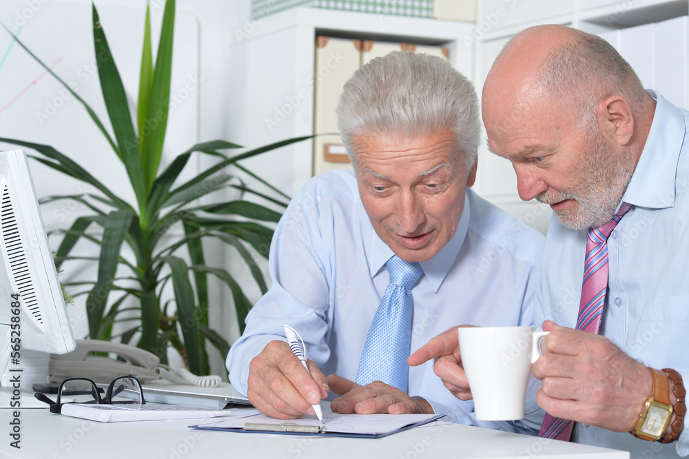 Two old business men sitting at desk and working Two old business men sitting at desk and working