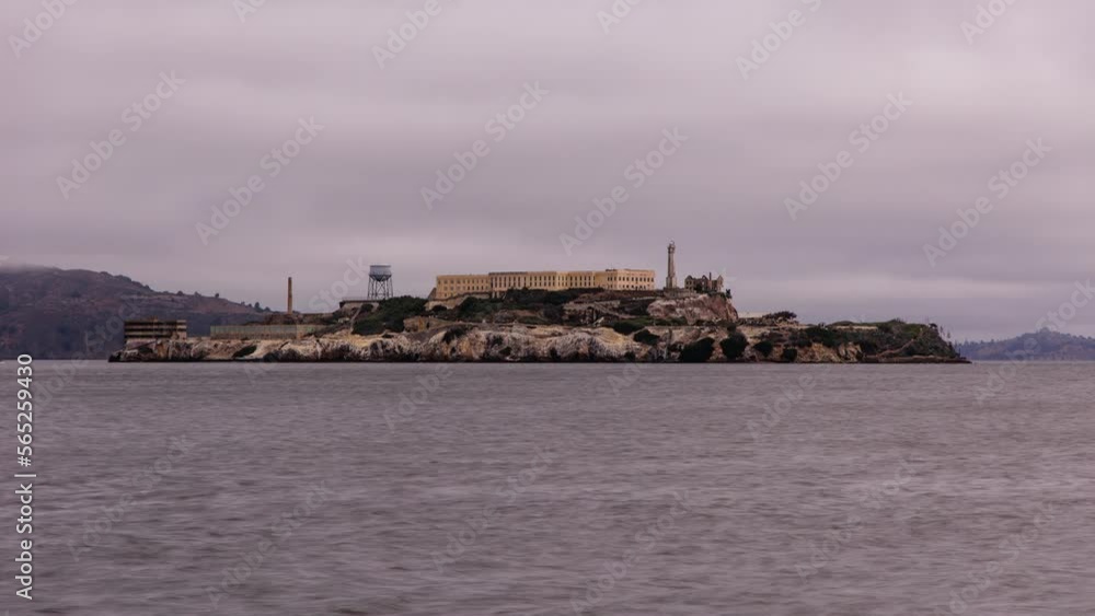 Famous landmark Alcatraz Island in the San Francisco Bay seen from San Francisco. Boats passing by, some rays of sunlight hitting the island.