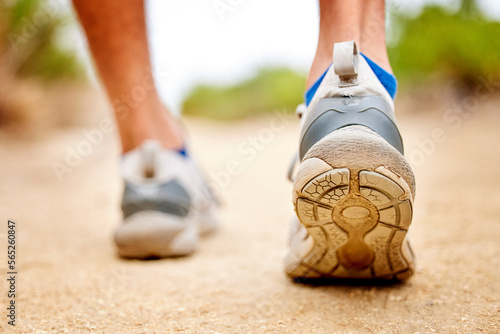 Fitness, shoes and sports person walking, running and man training on path. Back closeup of runner, feet and sneakers on ground for exercise, park workout and outdoor trekking, hiking and wellness