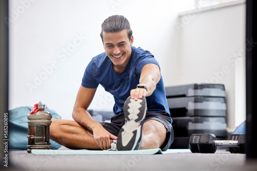 Fitness, gym or man stretching legs starting training, workout or exercise warm up to relax muscles. Wellness, flexible or healthy sports athlete with a happy smile exercising in a studio in Brazil