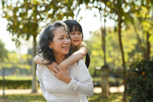 Photography Smiling mature grandmother giving piggyback ride to cute little granddaughter du