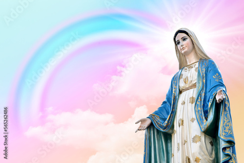 Statue of Our lady of grace virgin Mary with Fantasy magical landscape the rainbow on sky abstract with a pastel colored and wallpaper at Thailand.