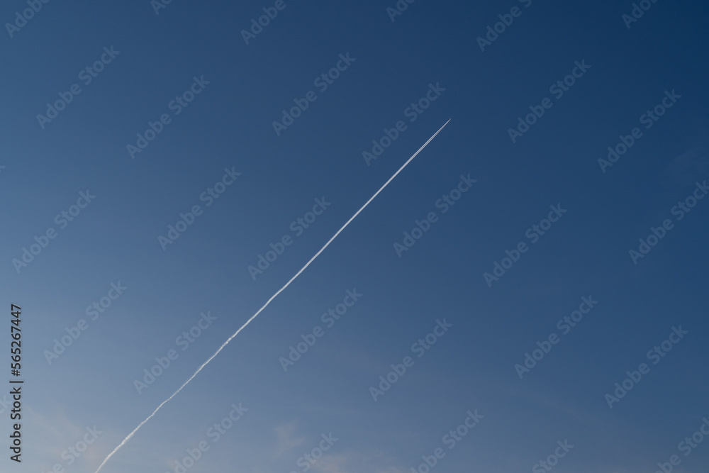 Flying airplane with contrails in the blue sky Flying airplane with contrails in the blue sky