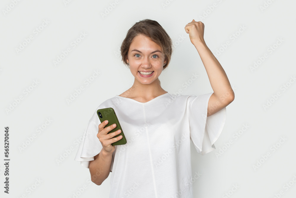 Happy excited joyful woman holding mobile cell phone shouting say yes, good news, celebrating success, winning Happy excited joyful woman holding mobile cell phone shouting say yes, good news, celebrating success, winning