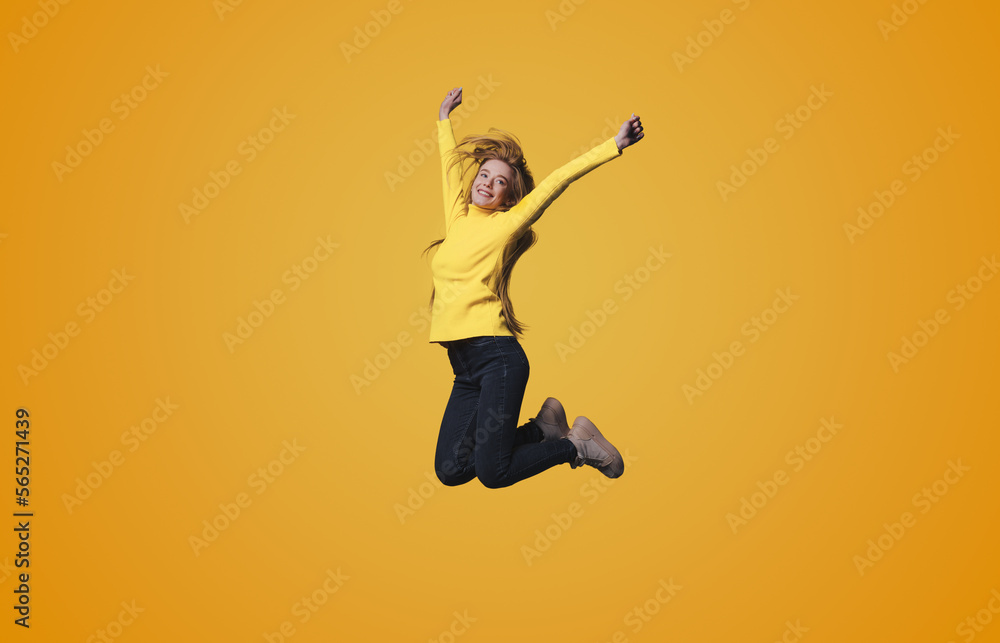 Full length body size photo of a woman jumping high gesturing like winner isolated on yellow color background.