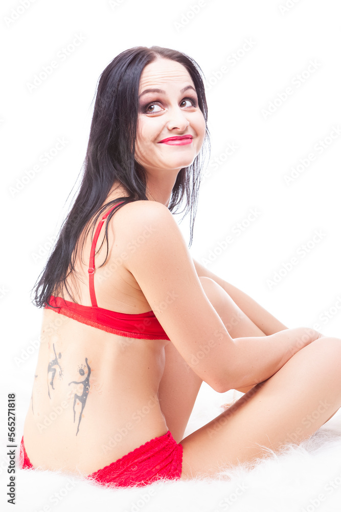 Obraz premium Smiling Cute Sensual Brunette Woman On Fur Blanket Posing in red Lingerie With Tattoo on Her Back And Looking Backwards.