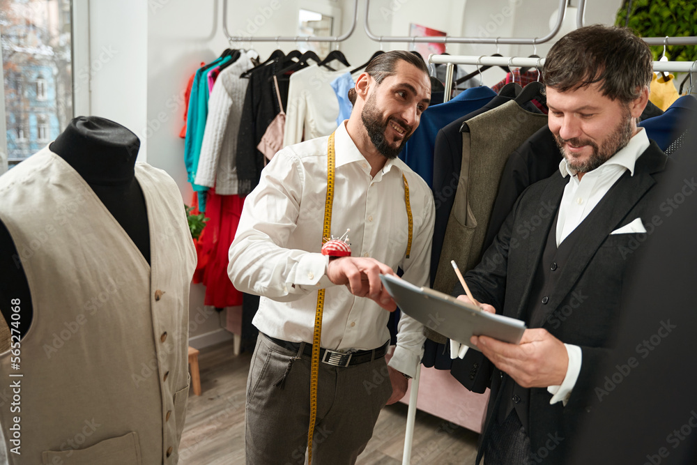 Contented customer filling out document in presence of clothier