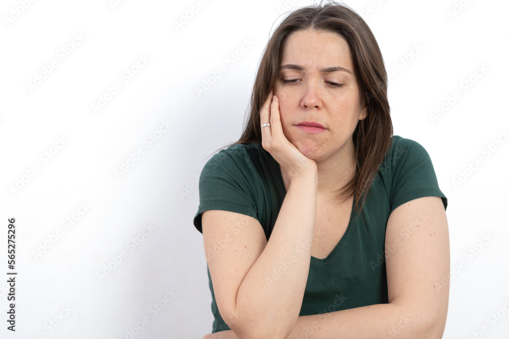 pensive woman looking at the ground with her hand on her face pensive woman looking at the ground with her hand on her face