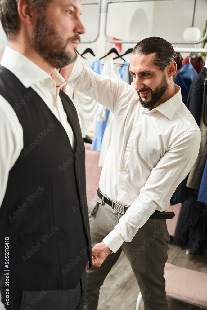 Contented tailor taking body measurements on man