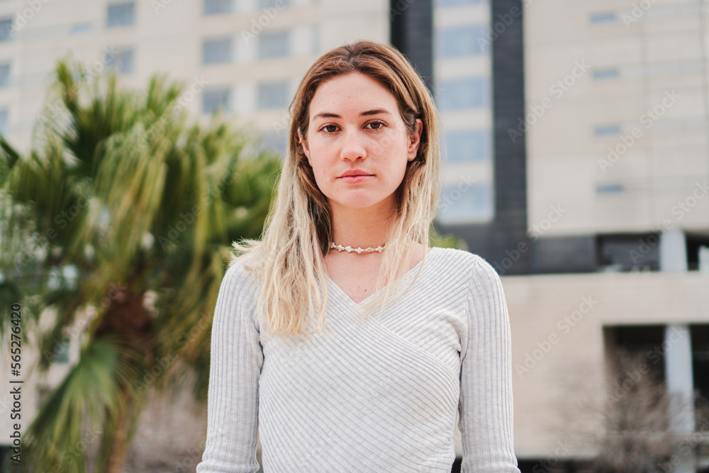 Obraz premium Close up portrait of blonde caucasian young woman looking serious at camera. Pretty teenage girl staring front with sad attitude. High quality 4k footage
