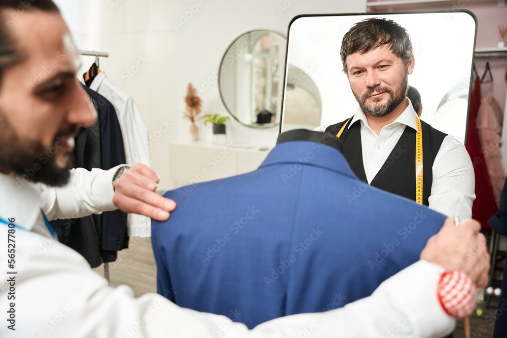 Obraz premium Two clothiers testing fit of garment on dummy