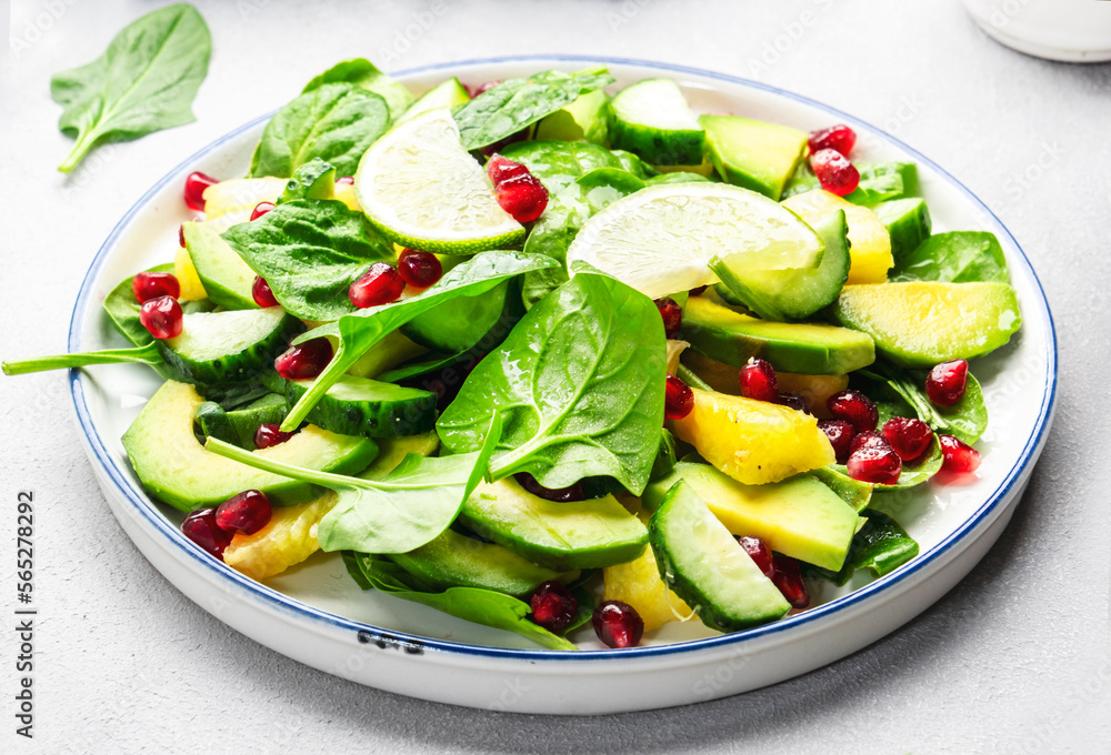 Fresh salad with pineapple, spinach, avocado and pomegranate on gray kitchen table, top view. Healthy vegan eating, clean food, diet, weight loss dish Fresh salad with pineapple, spinach, avocado and pomegranate on gray kitchen table, top view. Healthy vegan eating, clean food, diet, weight loss dish