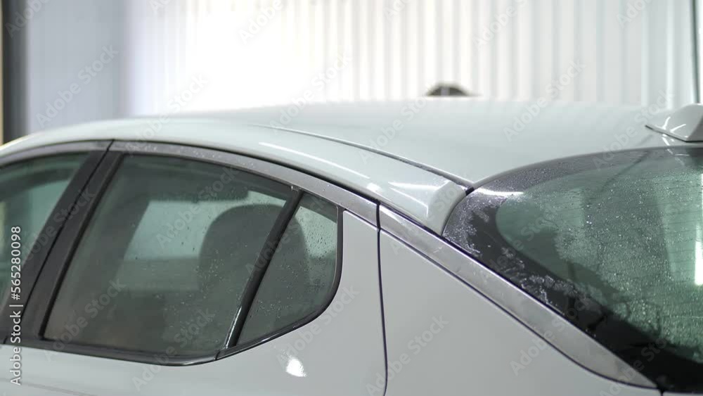Worker in garage automobile service is washing a car in the suds by non-contact high pressure water washer. Close-up washing the white transport. Car cleaning. Wash the auto at the car wash service. Worker in garage automobile service is washing a car in the suds by non-contact high pressure water washer. Close-up washing the white transport. Car cleaning. Wash the auto at the car wash service.