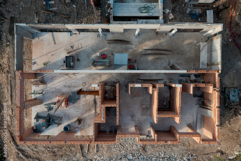 Aerial drone view of an outbuilding under construction, roofless with walls made of bricks.