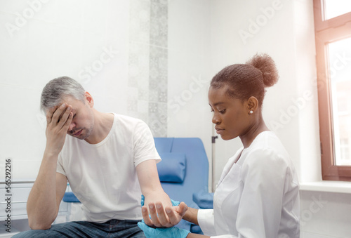 An African-American female doctor soothes a patient suffering from a severe headache