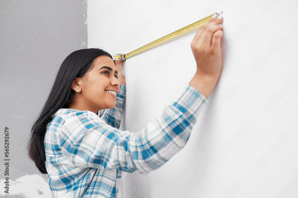 An Indian woman measures against the wall using measuring tape doing home DIY An Indian woman measures against the wall using measuring tape doing home DIY