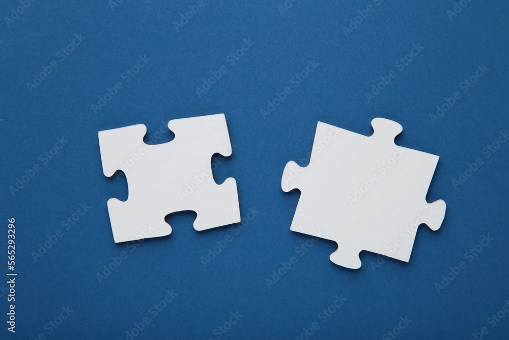 Obraz premium Two blank white puzzle pieces on blue background