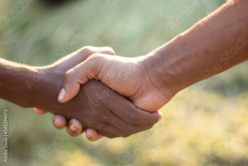 Two hands meet with one another hand and the background blurred © Rokonuzzamnan