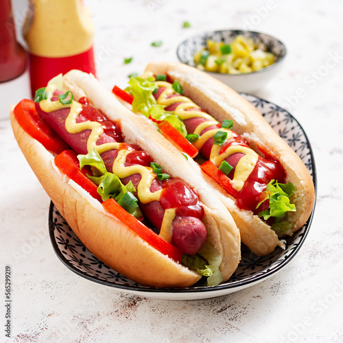 Hot dog with grilled sausage, tomato and lettuce on light background. American hot dog.