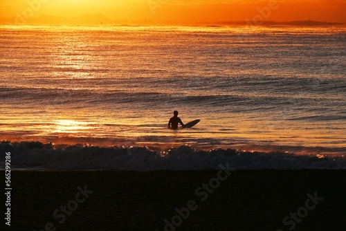 Surfers on the beach at dawn in winter.