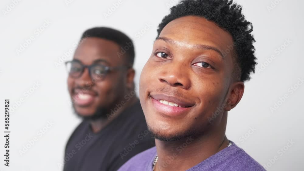 Happy black men. Positive mood. Model shooting. Smiling friendly guys posing staying in line on light wall background motion view. Happy black men. Positive mood. Model shooting. Smiling friendly guys posing staying in line on light wall background motion view.