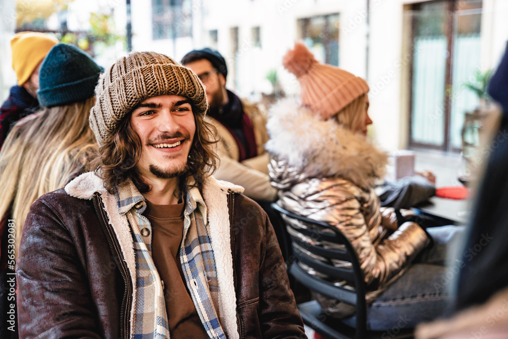Young trendy hipster guy wearing winter clothing having fun at pub -Happy group of friends sitting outdoors at restaurant enjoying together free time-Youth culture-Friendship and lifestyle concept Young trendy hipster guy wearing winter clothing having fun at pub -Happy group of friends sitting outdoors at restaurant enjoying together free time-Youth culture-Friendship and lifestyle concept