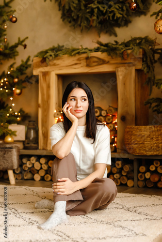 girl in a sweater and with bare legs sits near Christmas tree in Christams mood