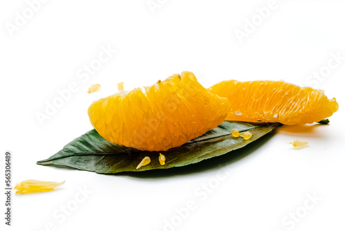 Peeled orange fruit pulp on green leaf isolated on white background. Macro photo of citrus fruit slice. Fresh, juicy pulp of orange