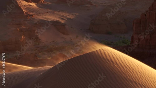 Sand blowing over dune in wind in red canyon, Gobi desert. Mongolia