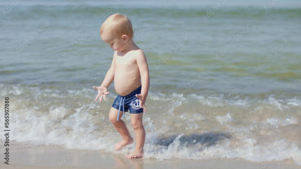 little baby boy toddler walking on sand beach coastline sea ocean cold water. child is scary of water runs away from waves. healthy lifestyle vacations bathing in sea ocean little baby boy toddler walking on sand beach coastline sea ocean cold water. child is scary of water runs away from waves. healthy lifestyle vacations bathing in sea ocean