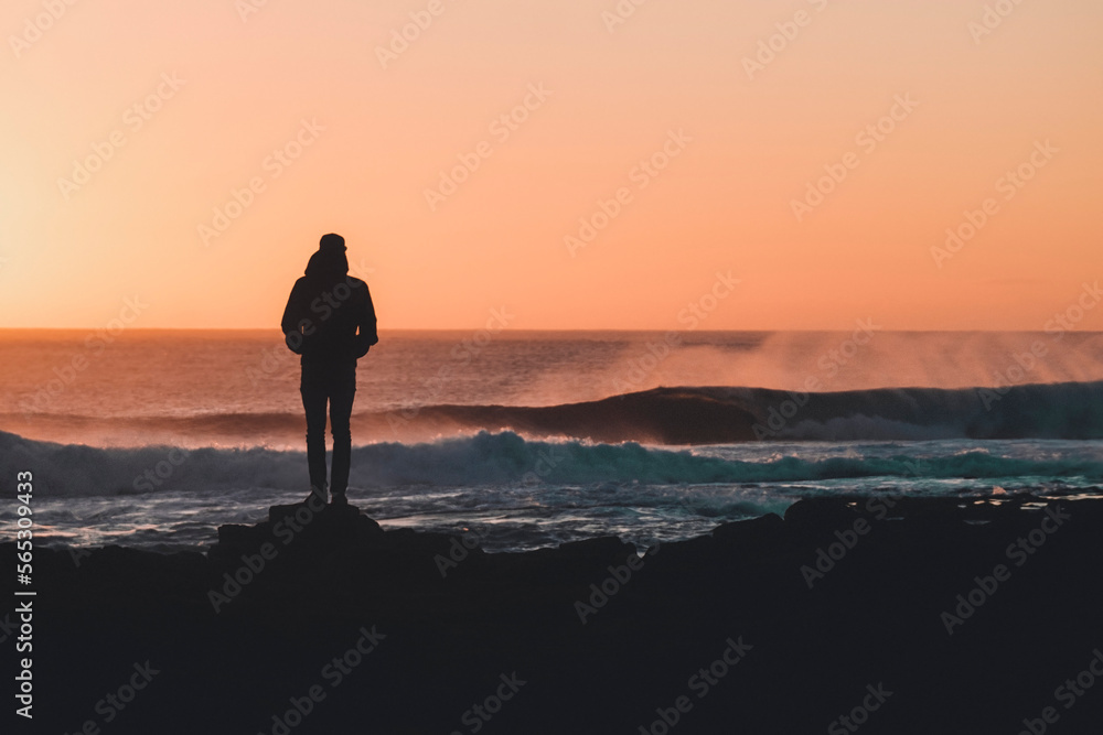 Silhouette of man looking at view of sea and waves at sunset, Fuerteventura, Canary Islands, Spain Silhouette of man looking at view of sea and waves at sunset, Fuerteventura, Canary Islands, Spain