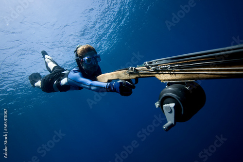 Underwater view of a female diving with a speargun toward the camera in the blue water of Costa Rica. photo