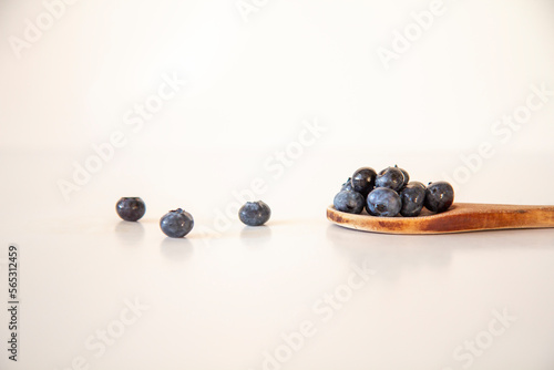 Blueberries on a wooden spoon, white background, loose berries, side view